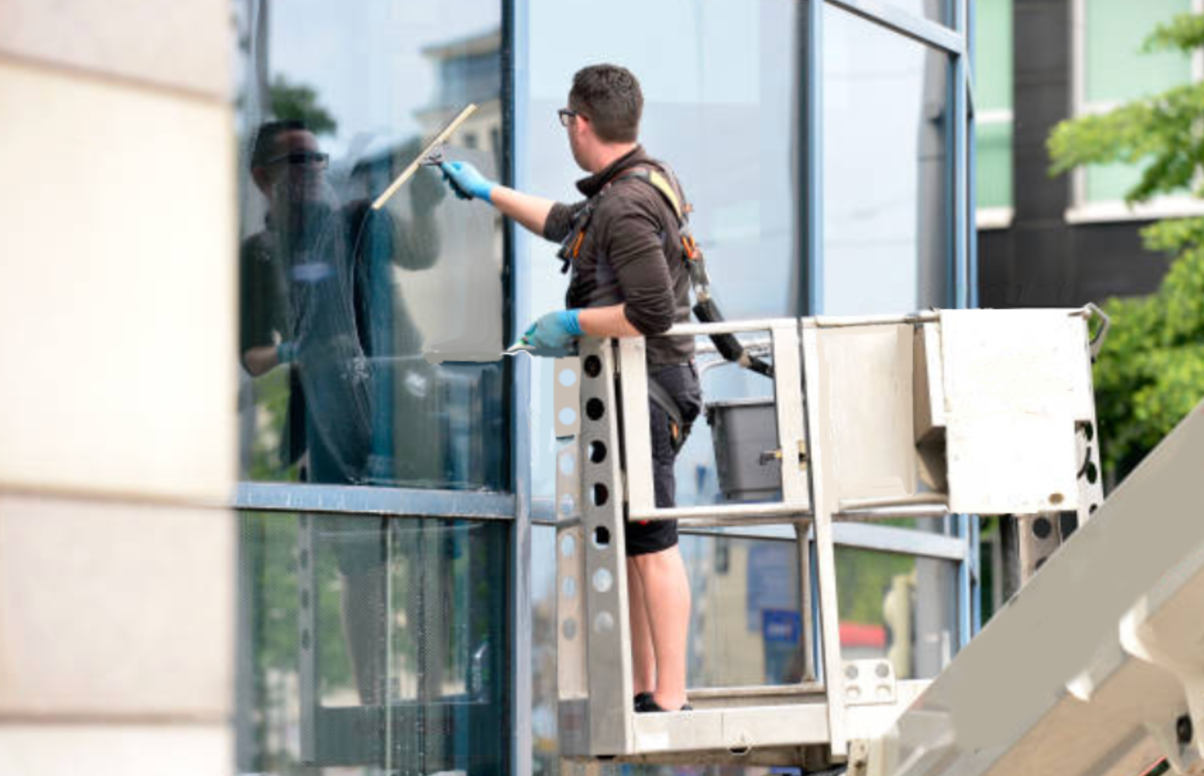 Window washers suspended on a glass skyscraper, cleaning windows on a sunny day.