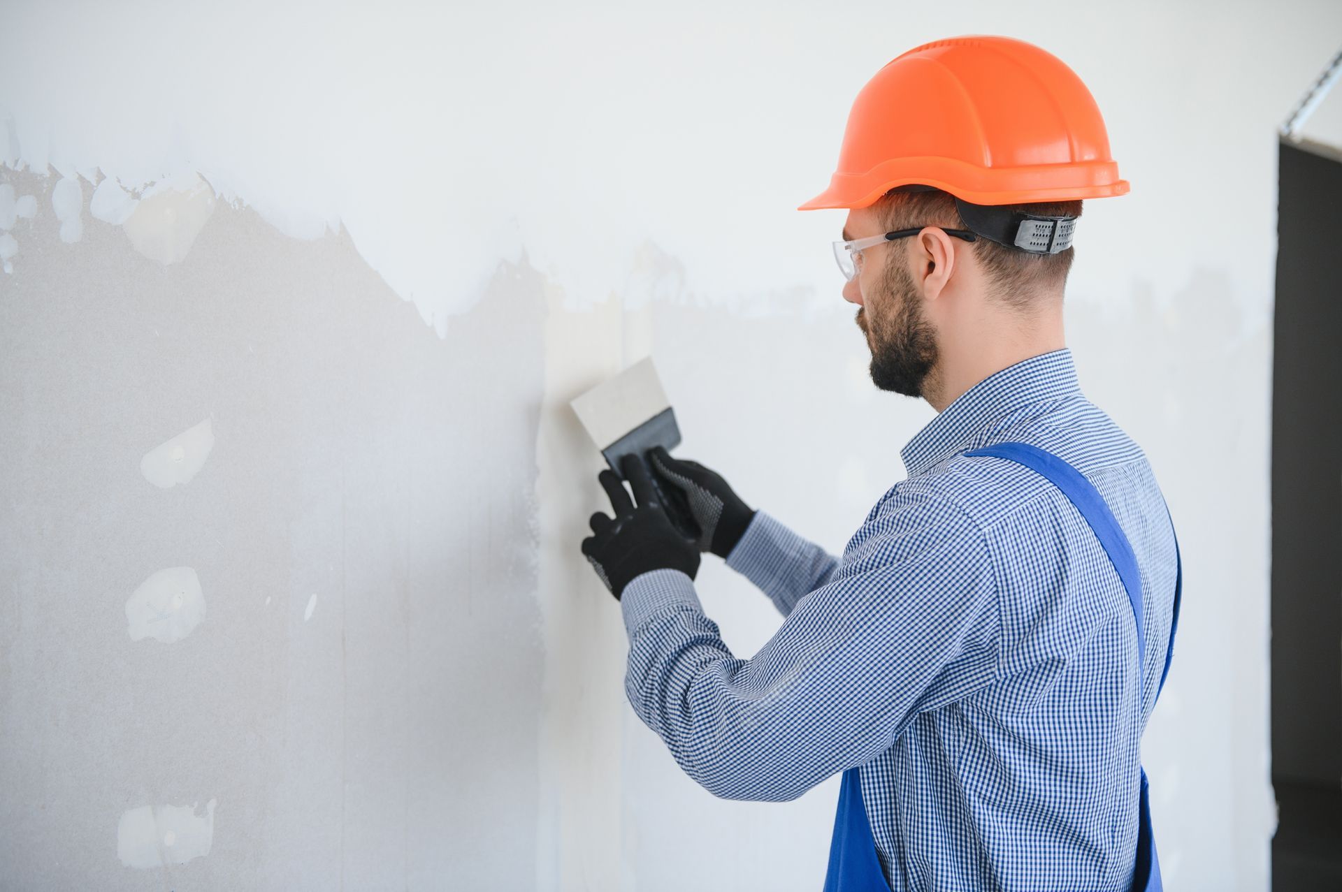 A Man is Plastering a Wall With a Spatula