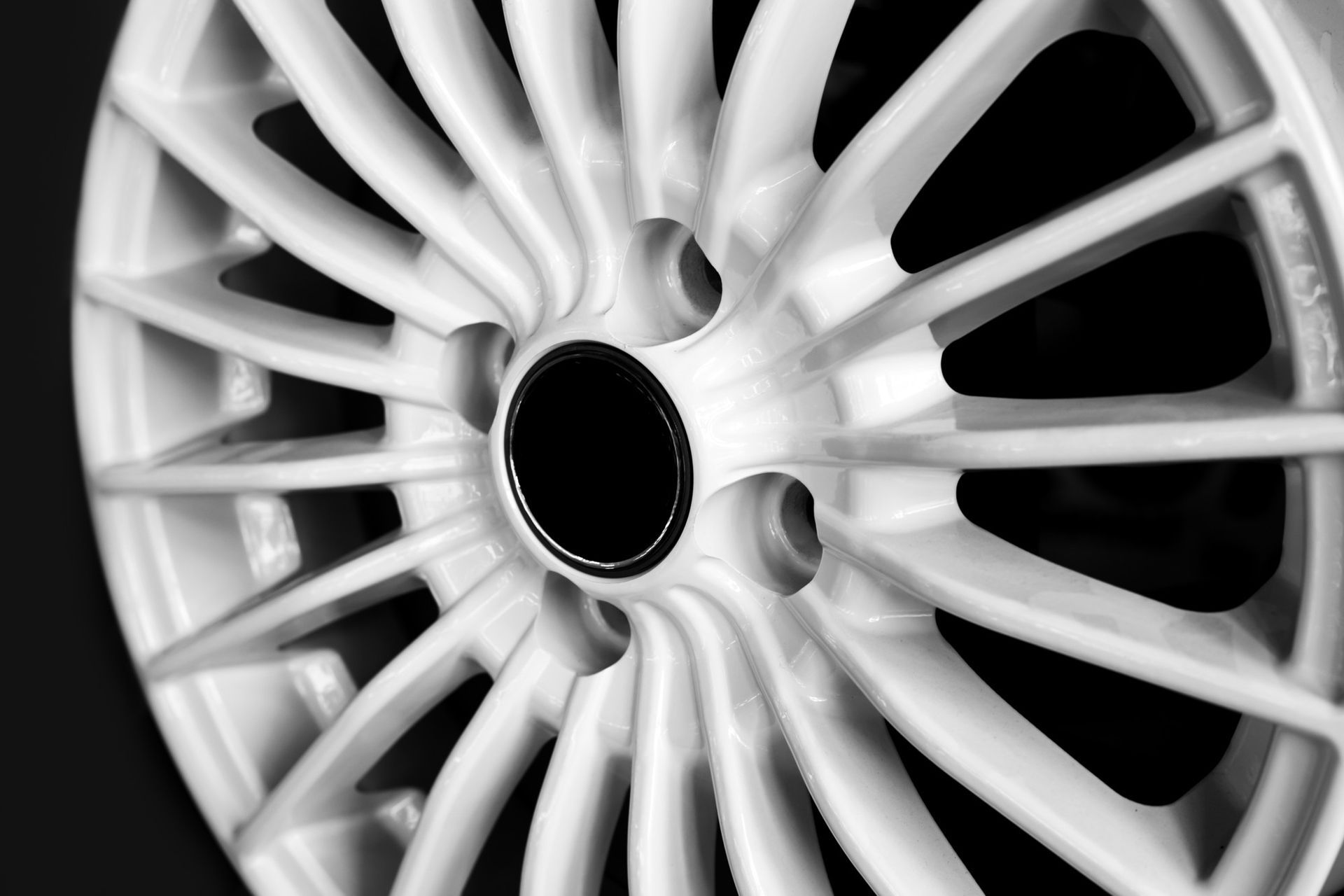 White car alloy wheel with black center against a black background.