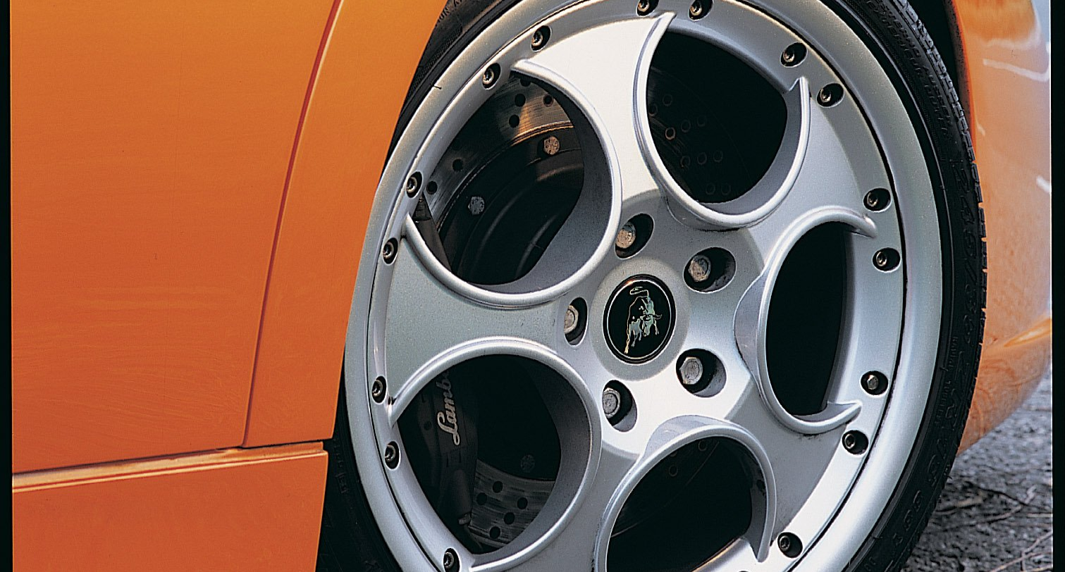 Silver Lamborghini wheel on an orange car, close-up.