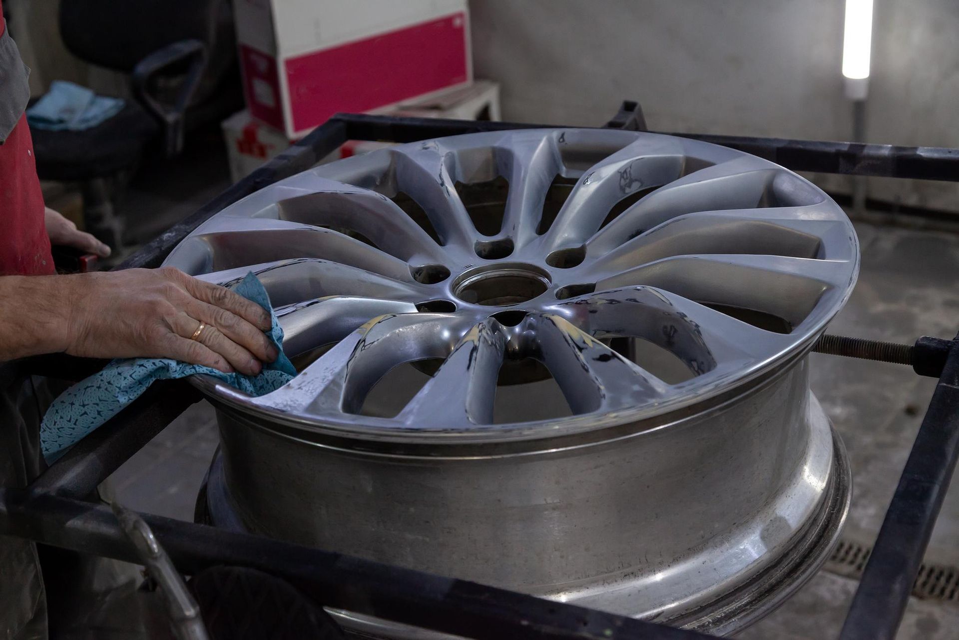A person is spraying paint on a wheel in a factory.