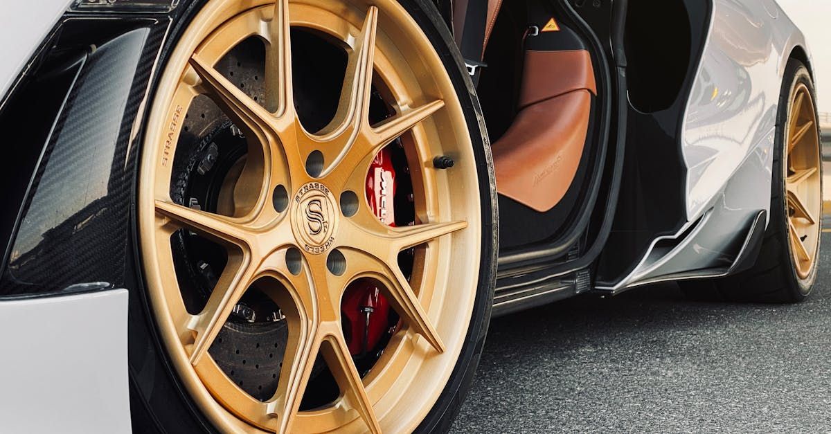 Gold alloy wheel on a black and brown sports car with red brake calipers.