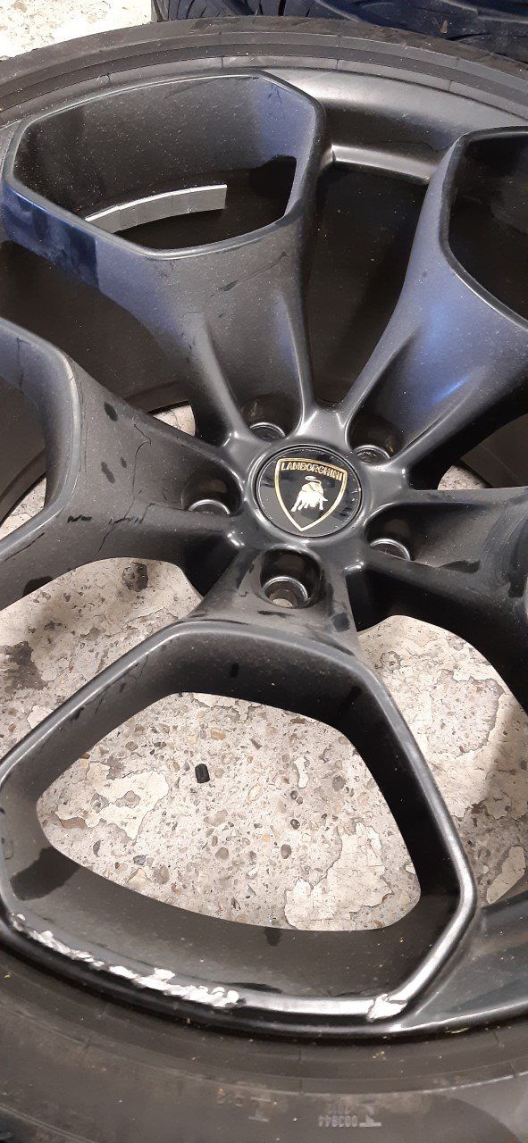 A close-up of a black Lamborghini rim with the brand logo at its center.