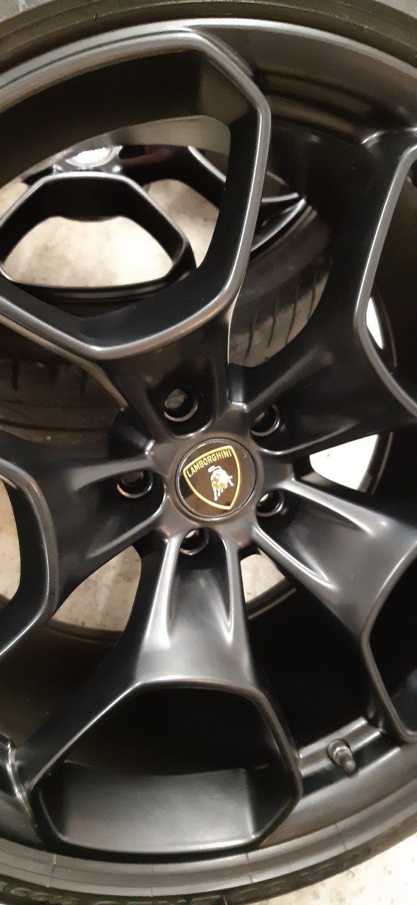 Black Lamborghini wheel with the brand logo at the center.