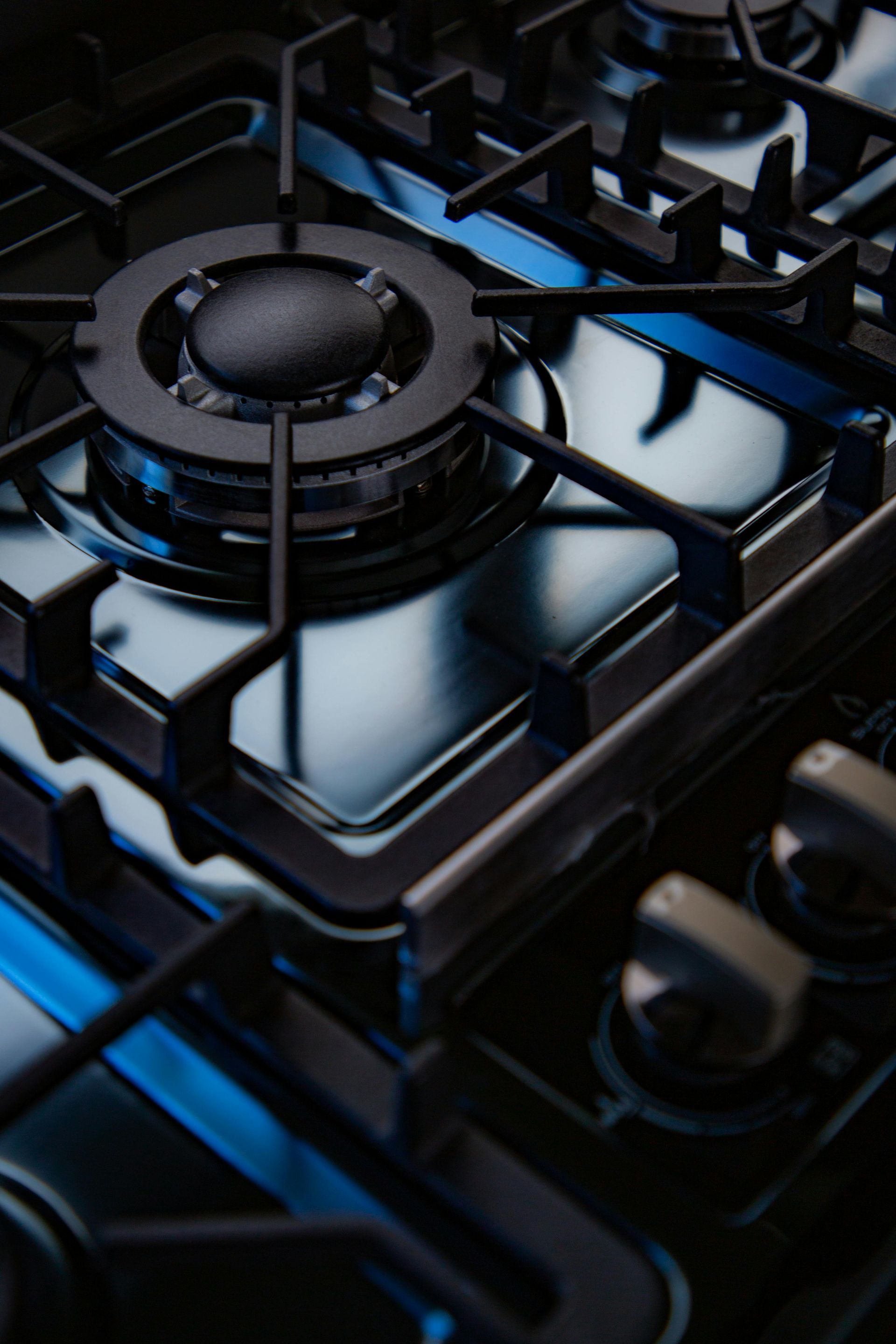 Close-up of a black gas stove burner with metal grates and blue highlights
