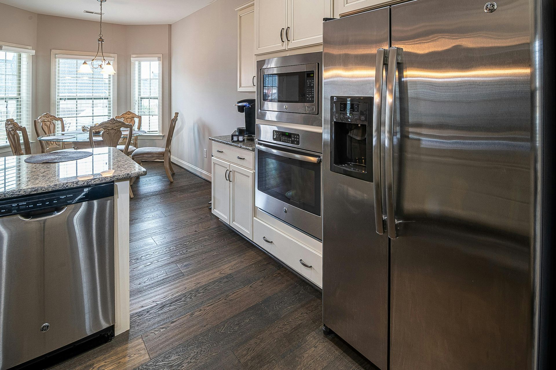 Modern kitchen with stainless steel appliances, white cabinets, and a dining area by the window