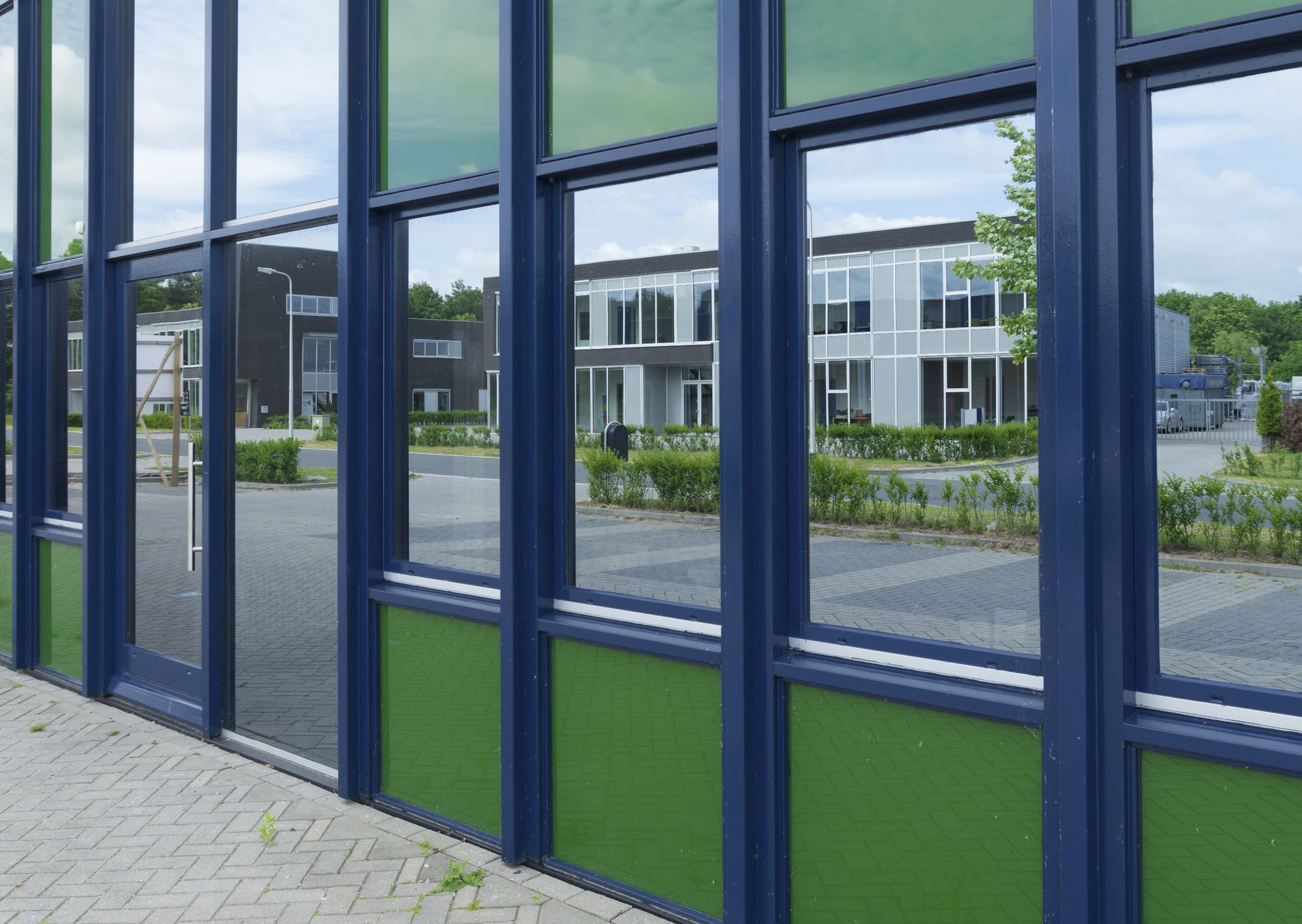 Blue-framed glass windows overlooking a modern office building and courtyard