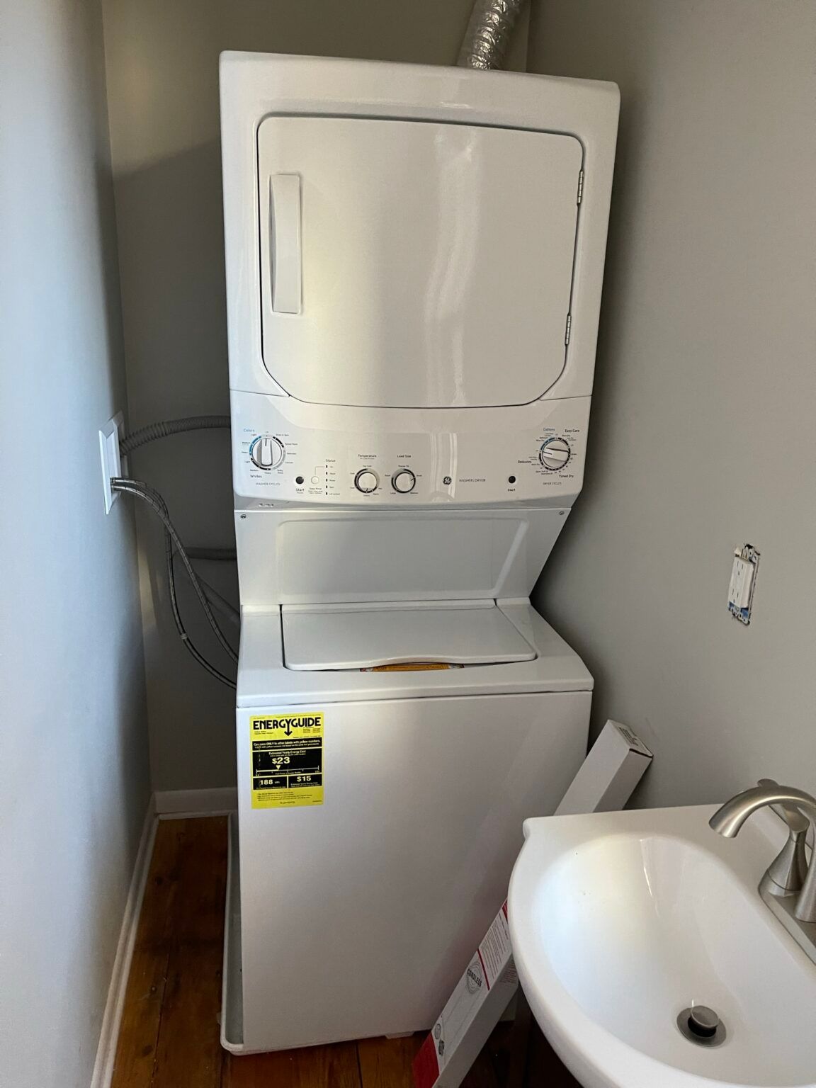 A washer and dryer are stacked on top of each other in a bathroom next to a sink.