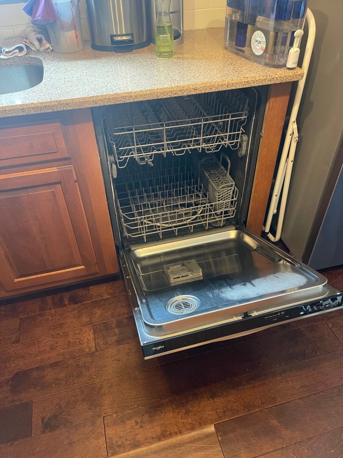 A dishwasher is open in a kitchen with the door open.