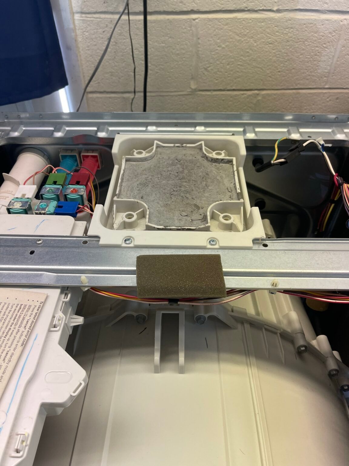 The inside of a refrigerator with the door open and a piece of foam on the floor.