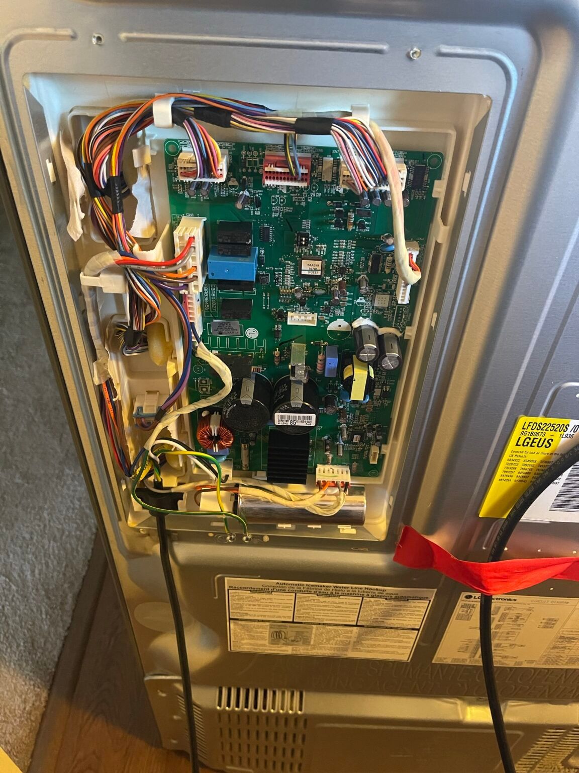 A refrigerator with the door open and a bunch of wires coming out of it.