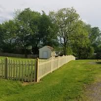 A white picket fence surrounds a lush green field.