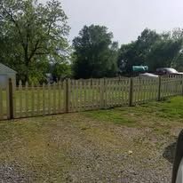 A car is parked in front of a wooden picket fence.