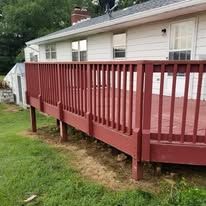 A red deck is in front of a white house.