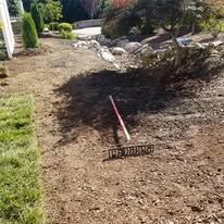 A rake is sitting on top of a pile of dirt in a garden.