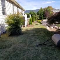 A lawn roller is sitting in the grass in front of a house.