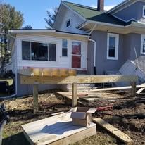 A wooden deck is being built in front of a house.