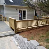 A man is standing on a wooden deck next to a house.