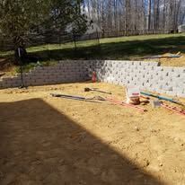 A brick wall is being built in the backyard of a house.
