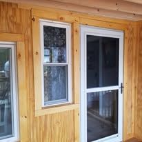 A wooden house with a screen door and two windows.