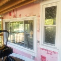 A window on the side of a house with pink insulation.