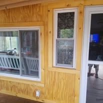 A wooden house with a sliding glass door and two windows.