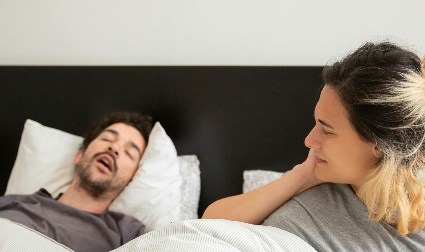 Men breathing with his mouth open while the couple lies in bed 