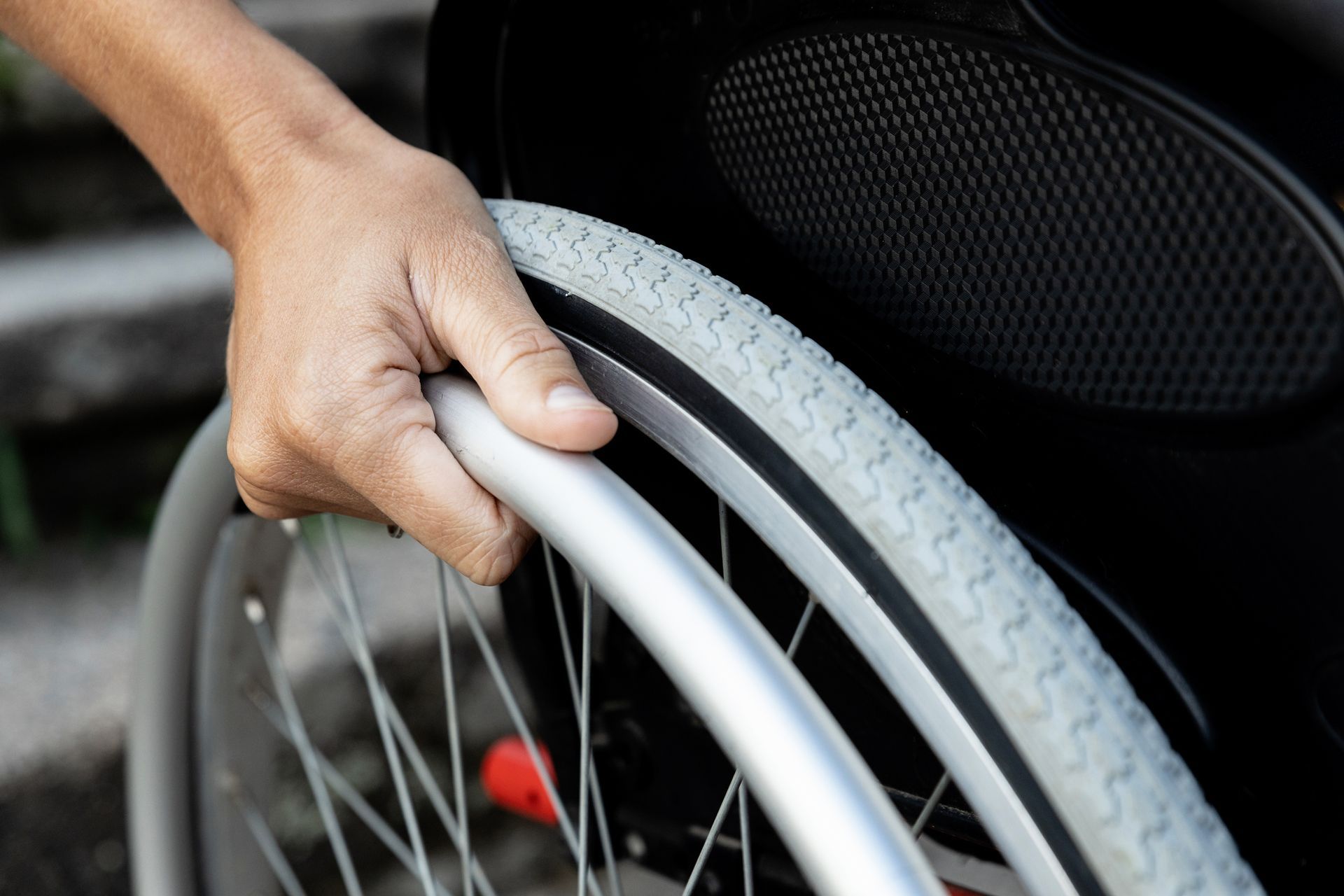A person is holding the wheel of a wheelchair.
