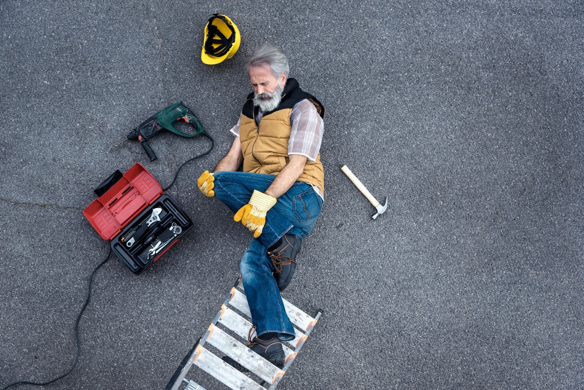 A man is sitting on a ladder on the ground.