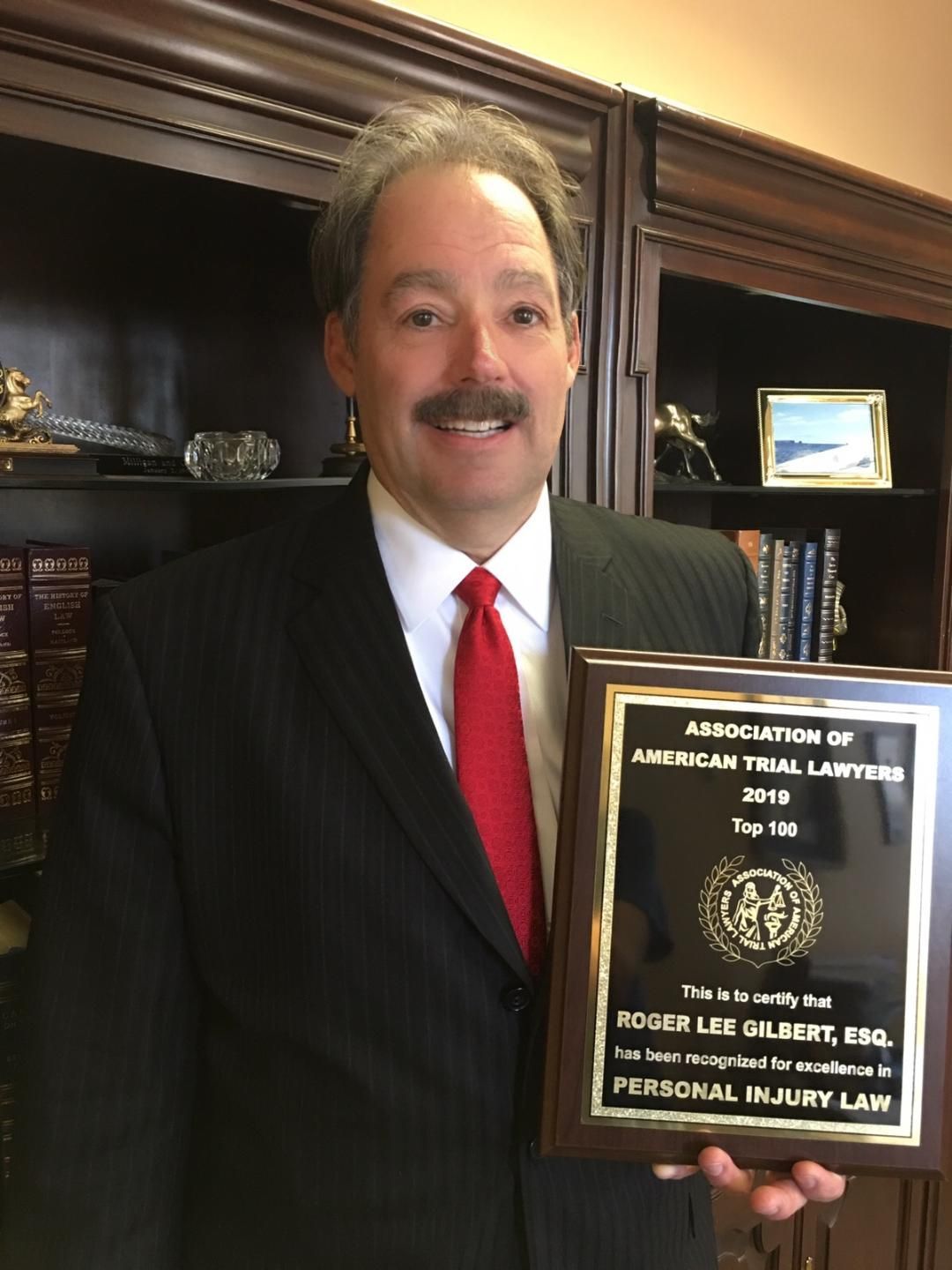 A man in a suit and tie is holding a plaque that says personal injury law