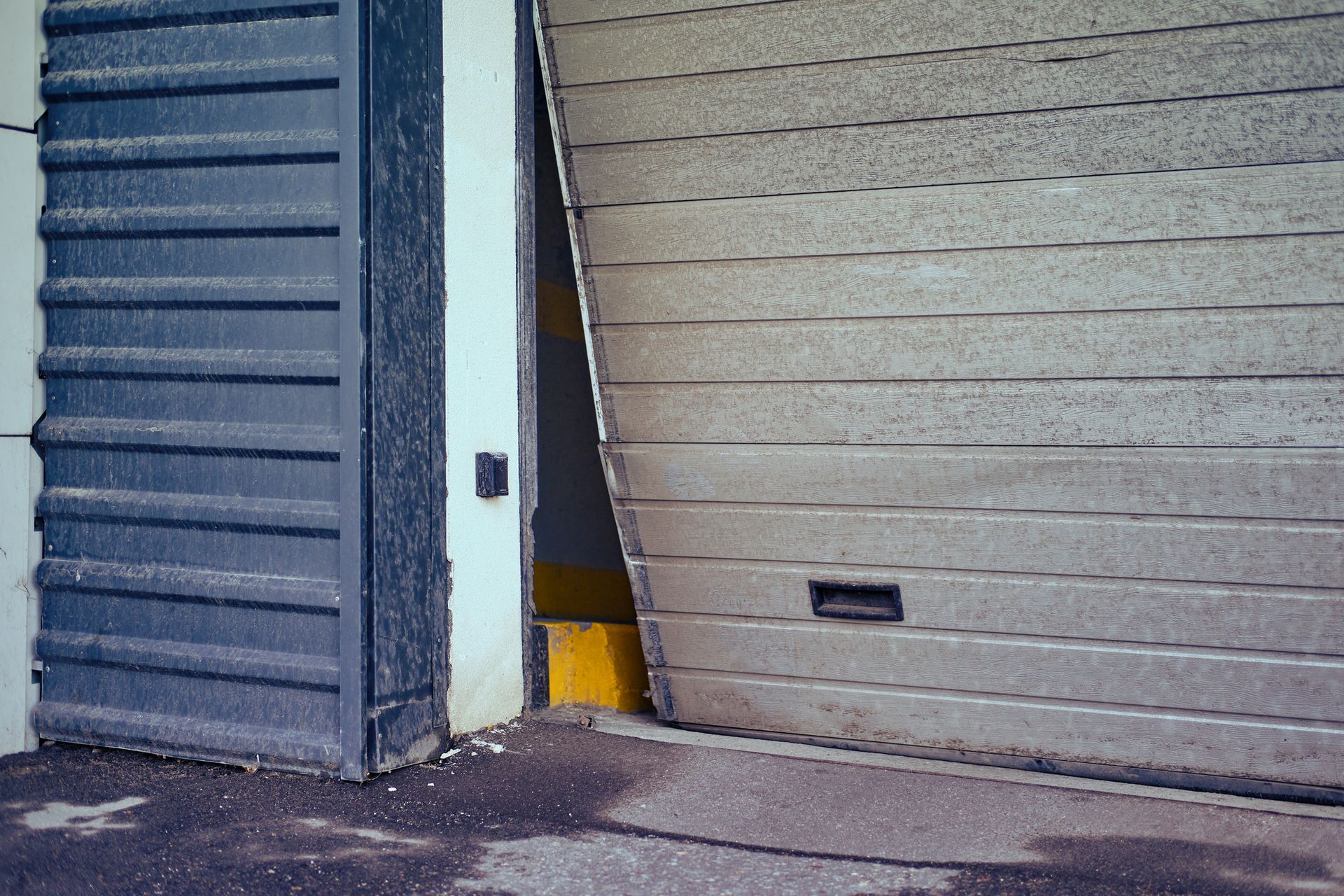 Garage door partially open, revealing a yellow interior. A dark gray door is on the left.