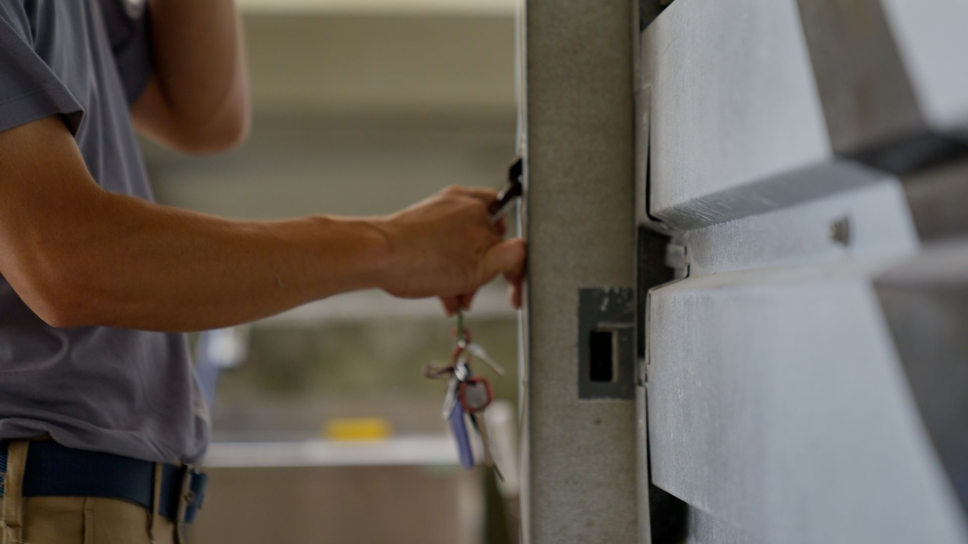 Person unlocking a metal gate with keys. Close-up of the hand and lock.