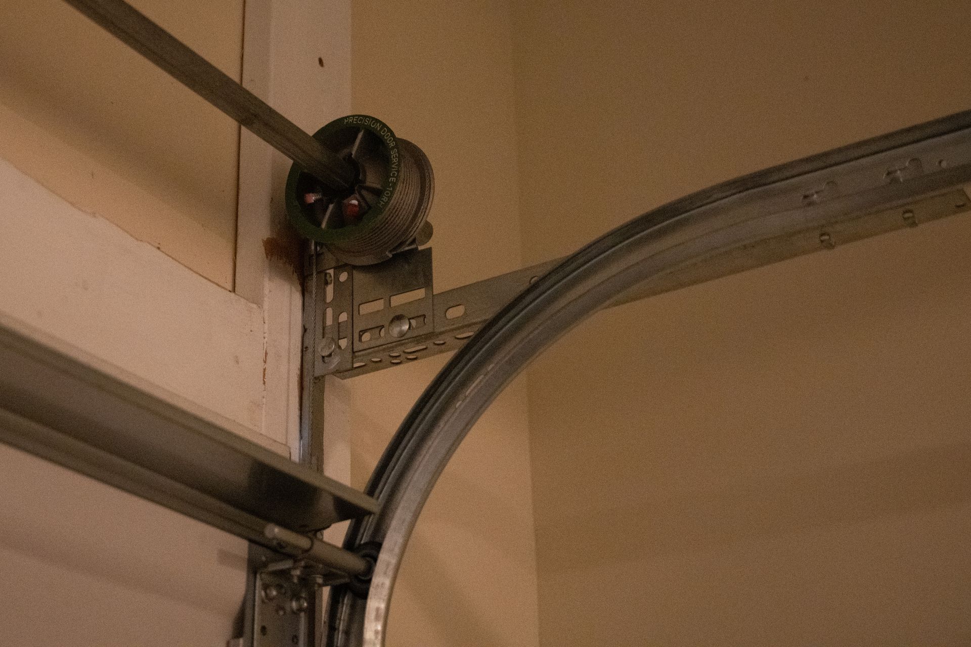 Garage door track with a curved rail, spring mechanism, and metal support frame.