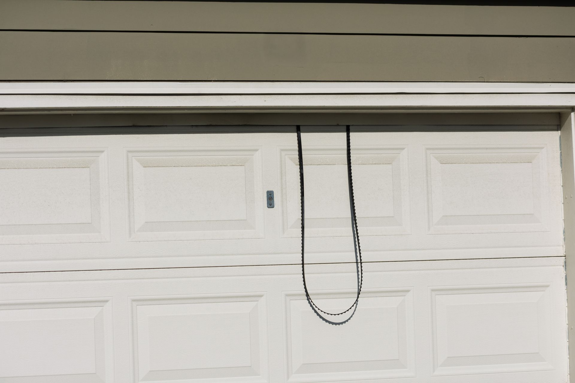 White garage door with black emergency pull cord hanging down.
