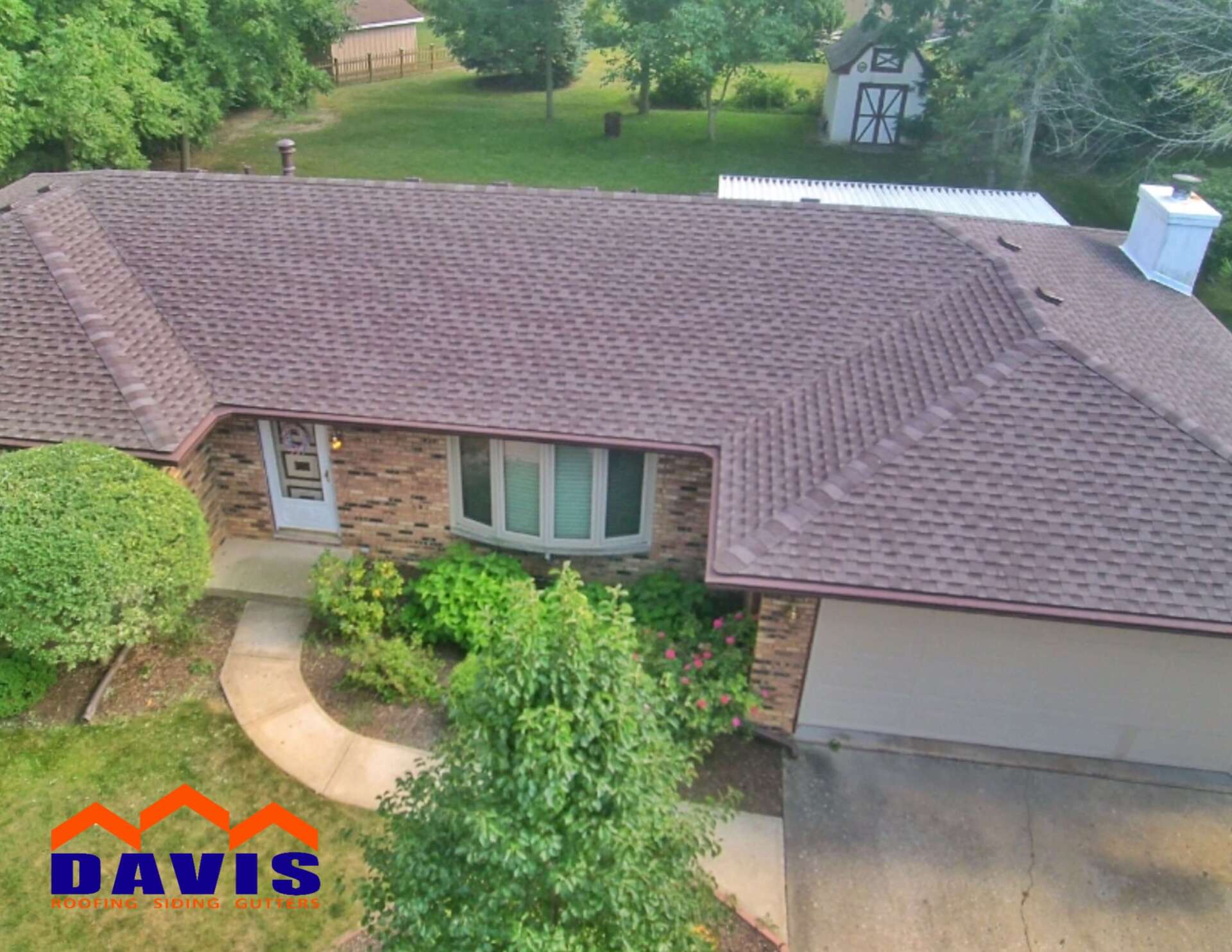 Brown shingle roof of a house from an aerial view, with a green yard and landscaping.