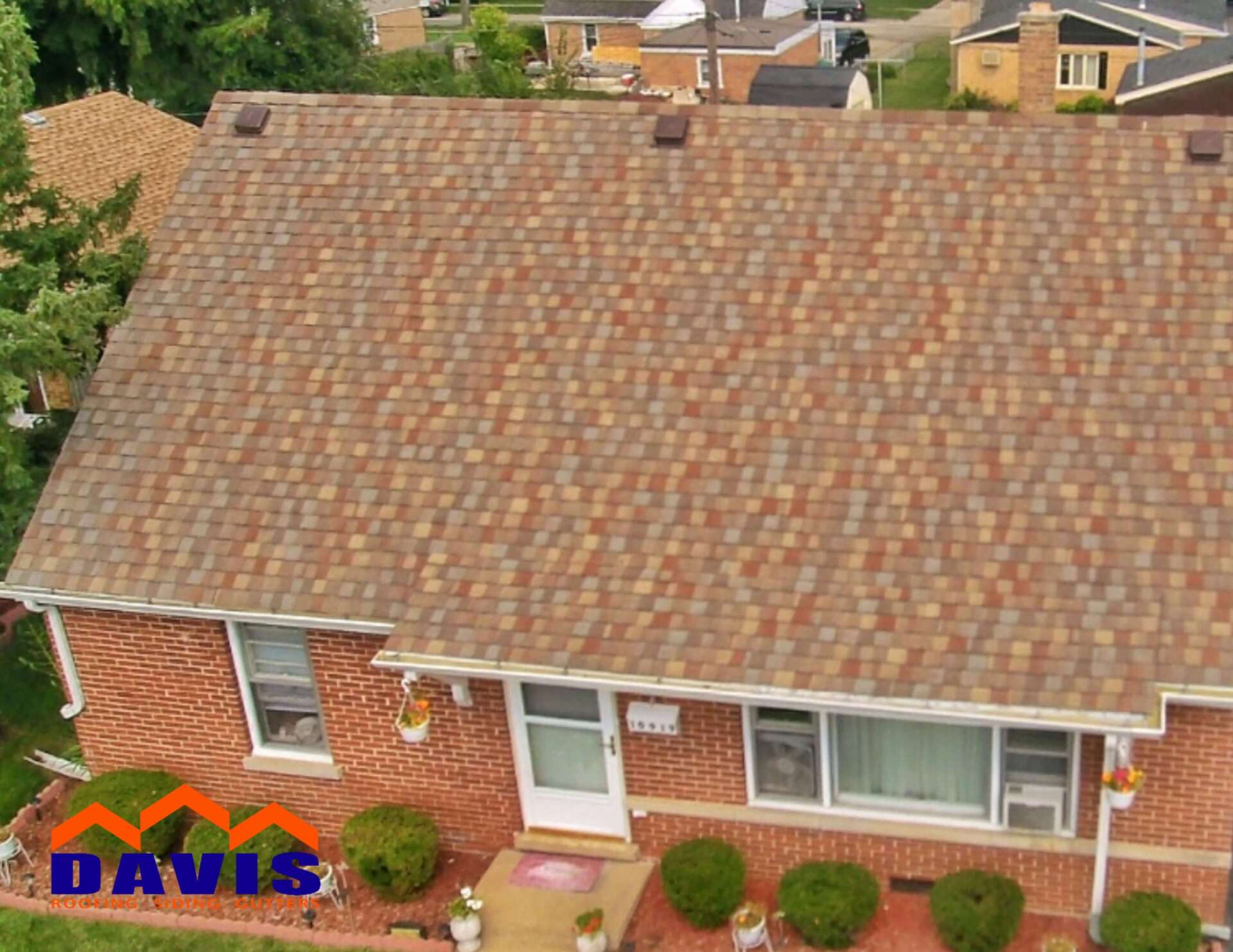 A brick house with a brown roof, windows, and a white door, with the Davis logo in the corner.