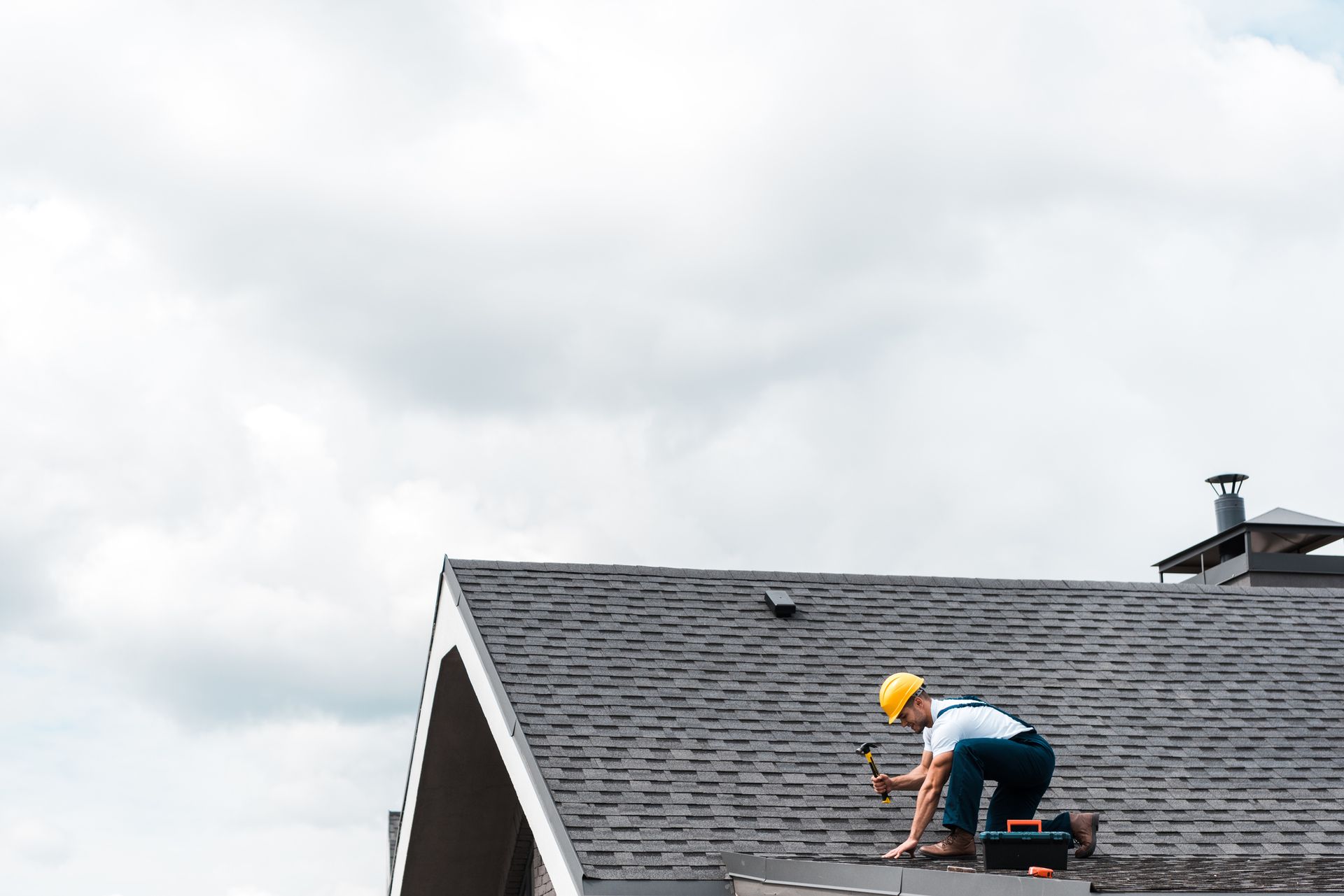 A repairman holding a hammer while repairing the roof.
