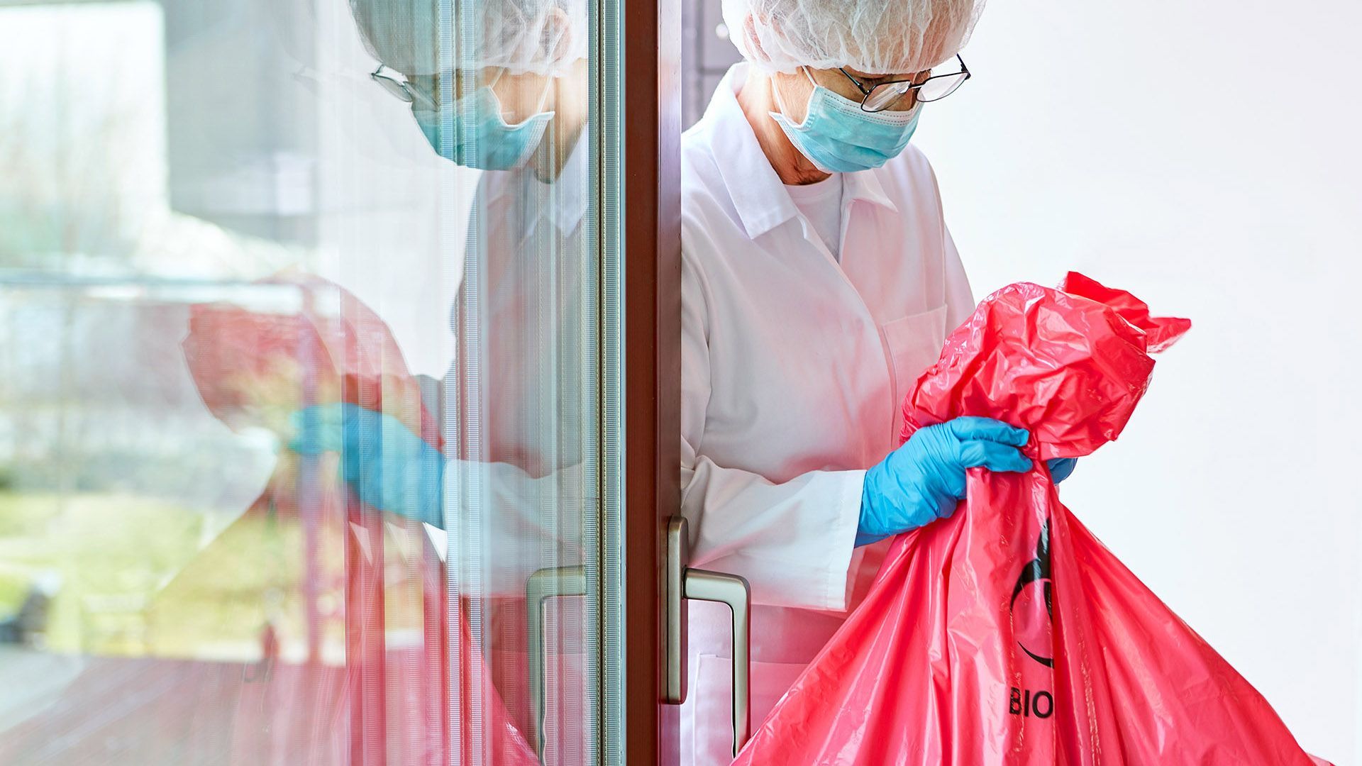 medical worker removing hazardous waste in a red bag