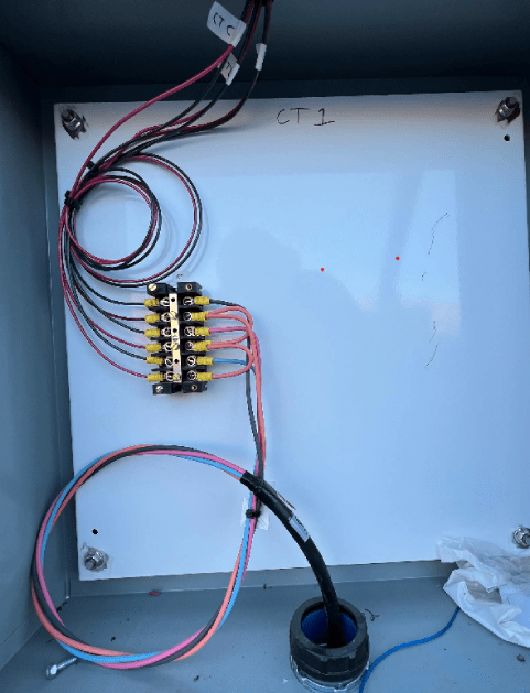 Electrical wiring inside a gray metal box with a white panel labeled 