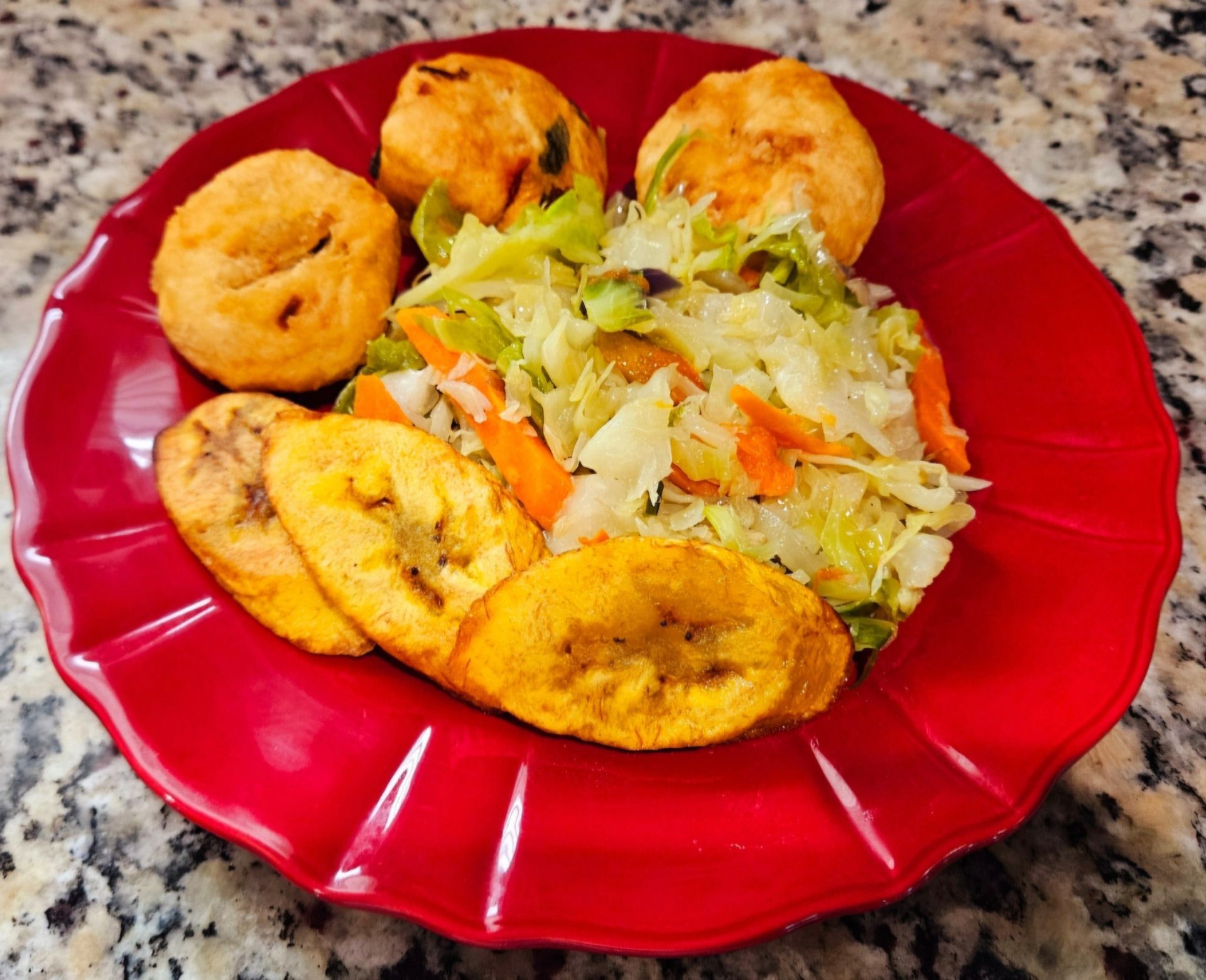 A red plate topped with fried plantains , cabbage and carrots.