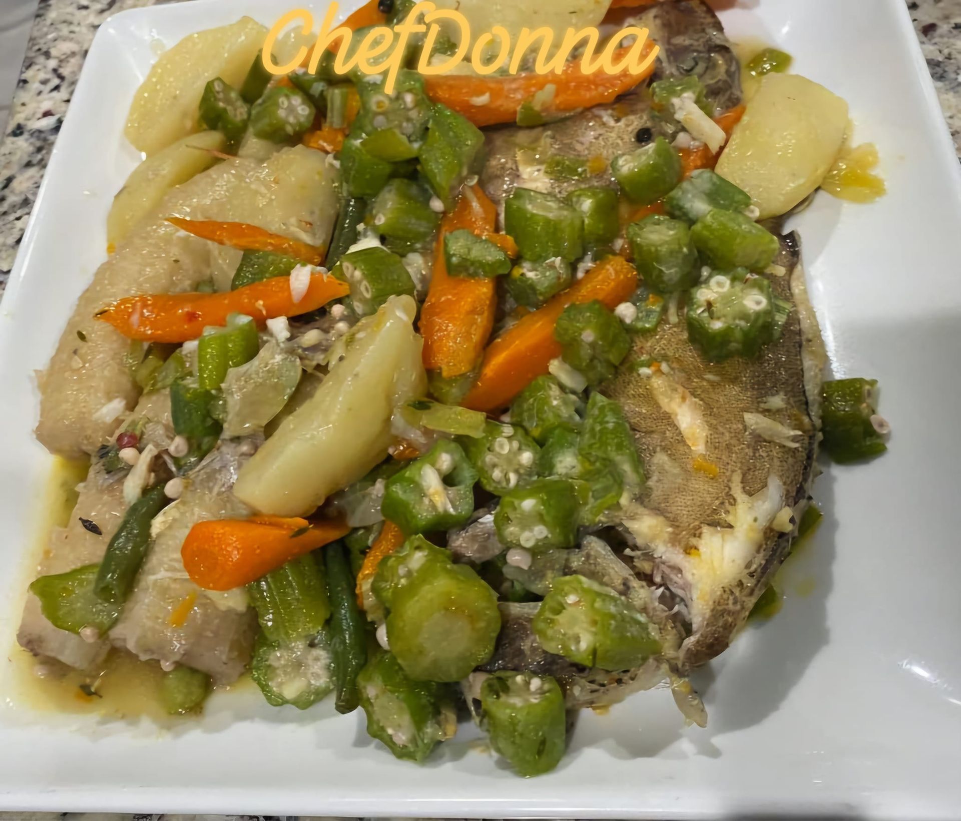 A plate of food with okra , carrots , and potatoes on a table.