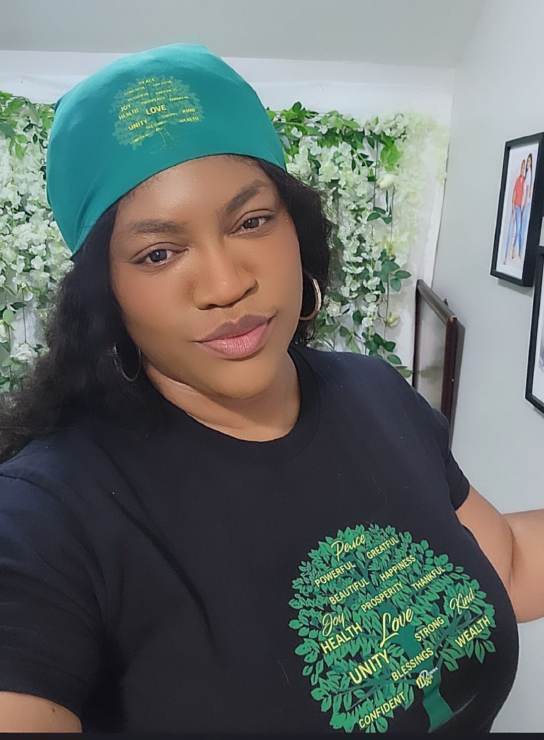 A woman wearing a green hat and a black shirt with a tree on it.