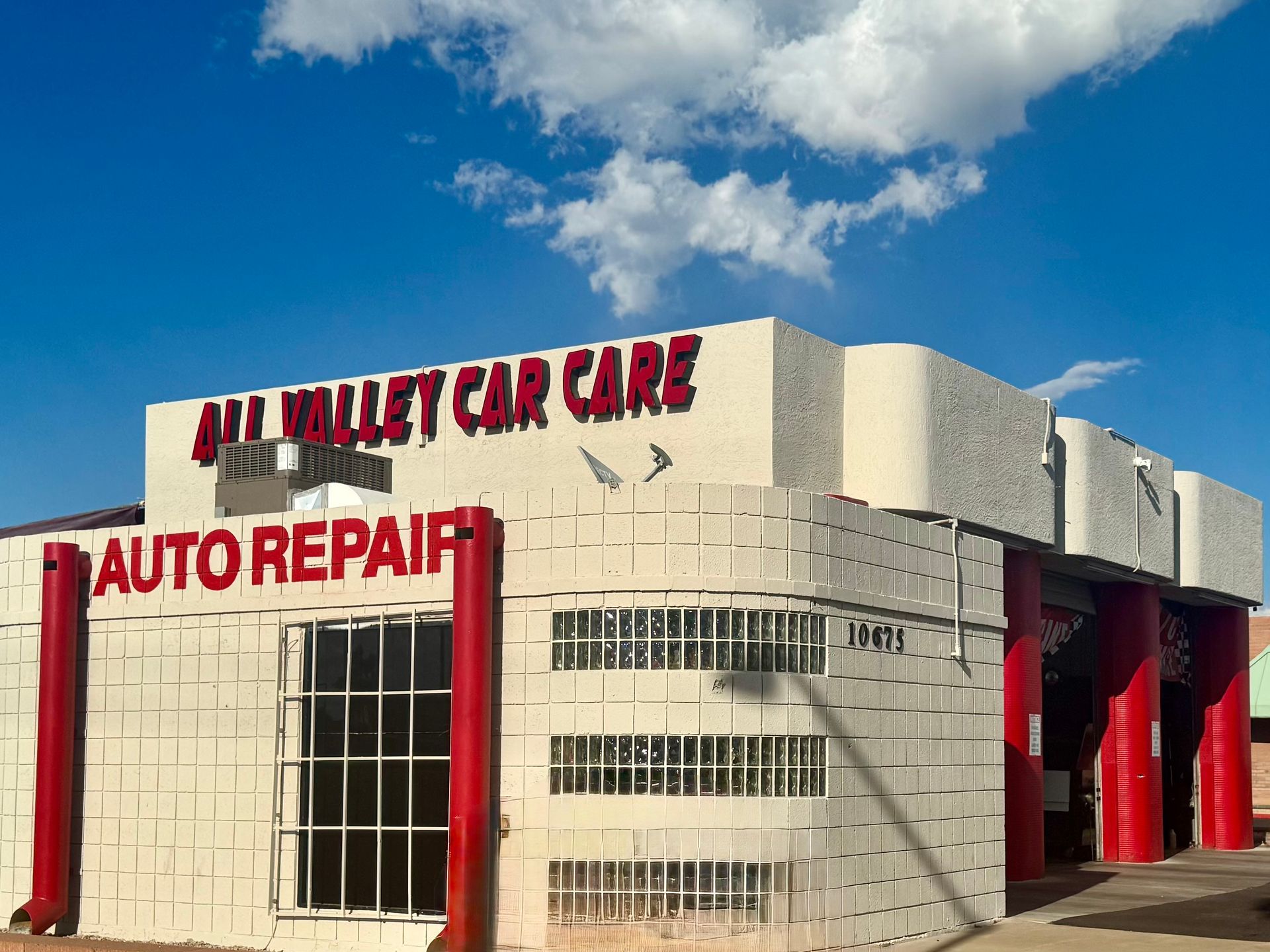 All Valley Car Care auto repair shop. Red and white building under a blue sky with clouds.