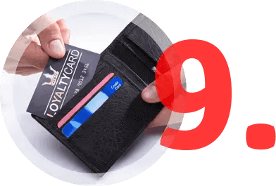 Hand holding a black wallet with credit cards and a loyalty card, with a large red 