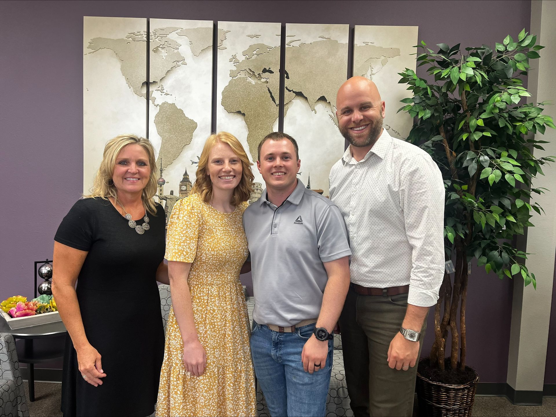 A group of people are posing for a picture in front of a map of the world.