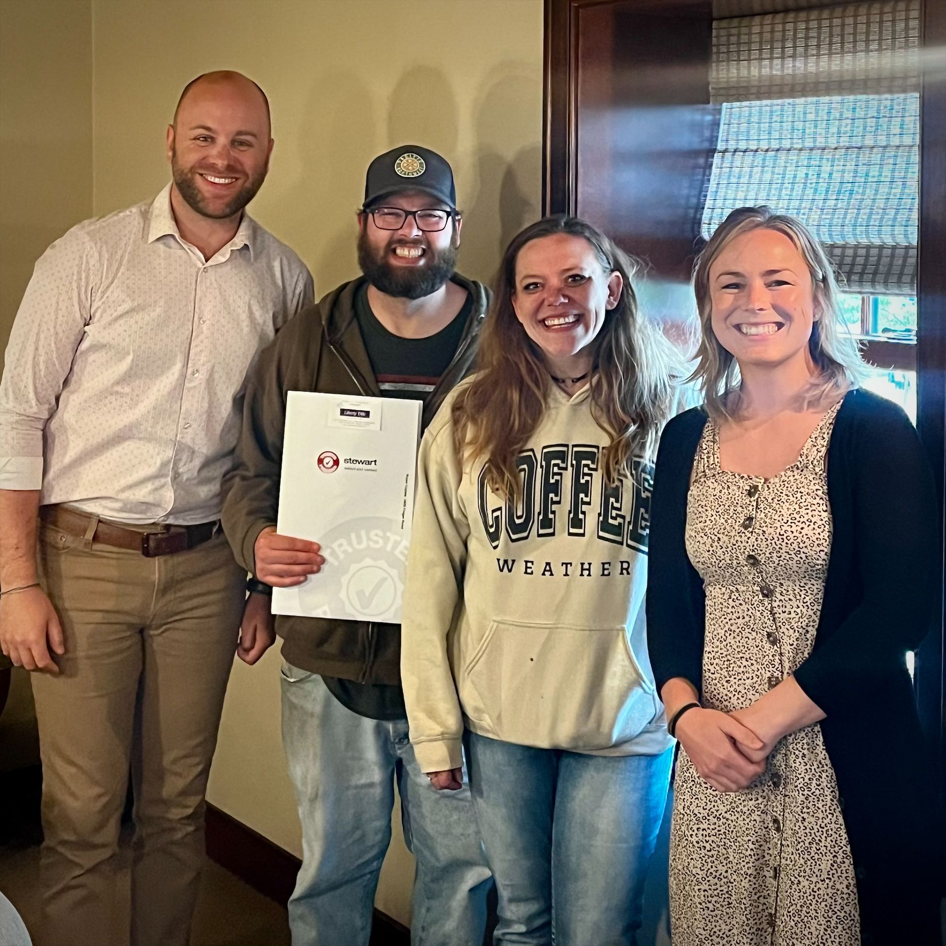 A group of people are posing for a picture and one of them is wearing a coffee sweatshirt