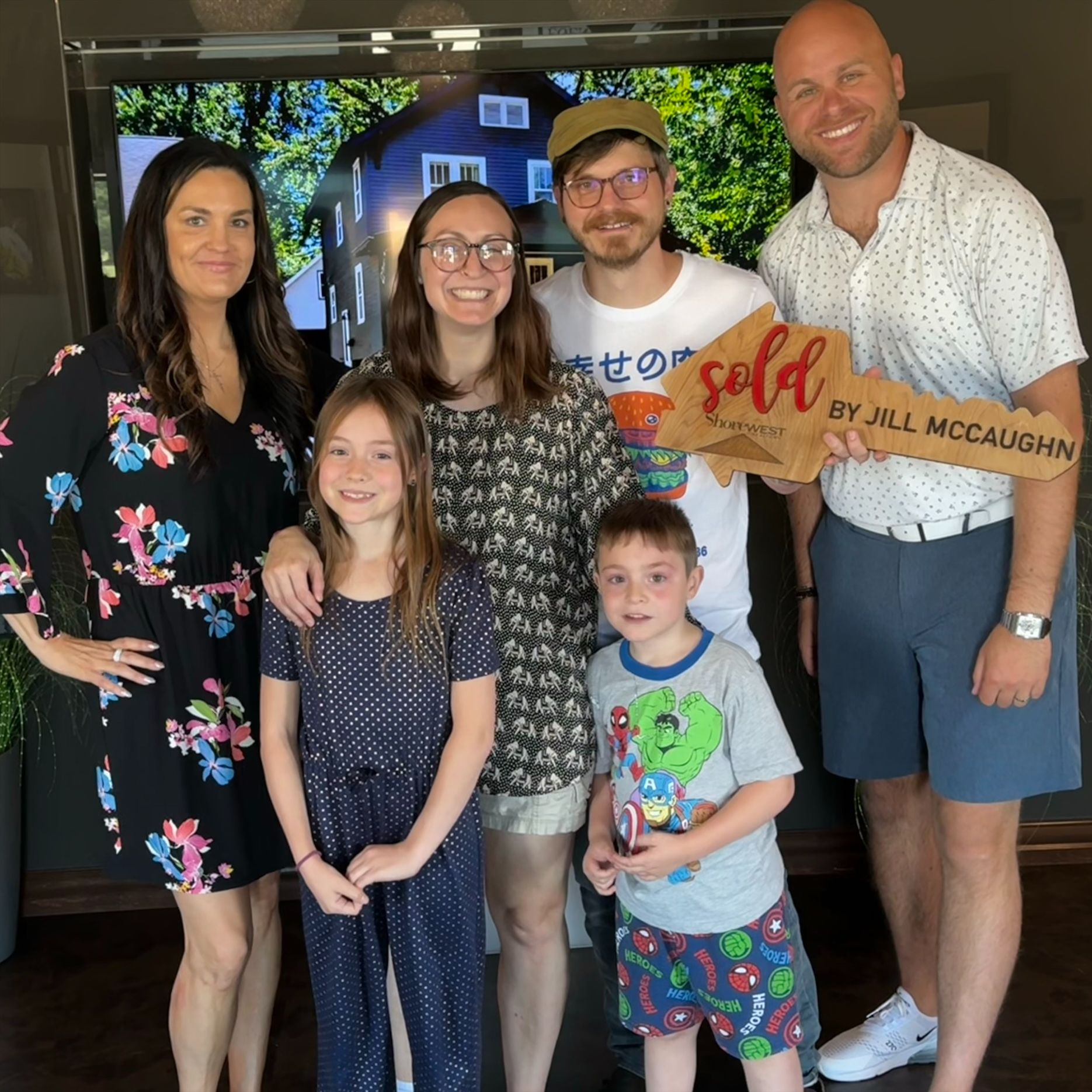 A group of people standing around a man holding a sold sign.