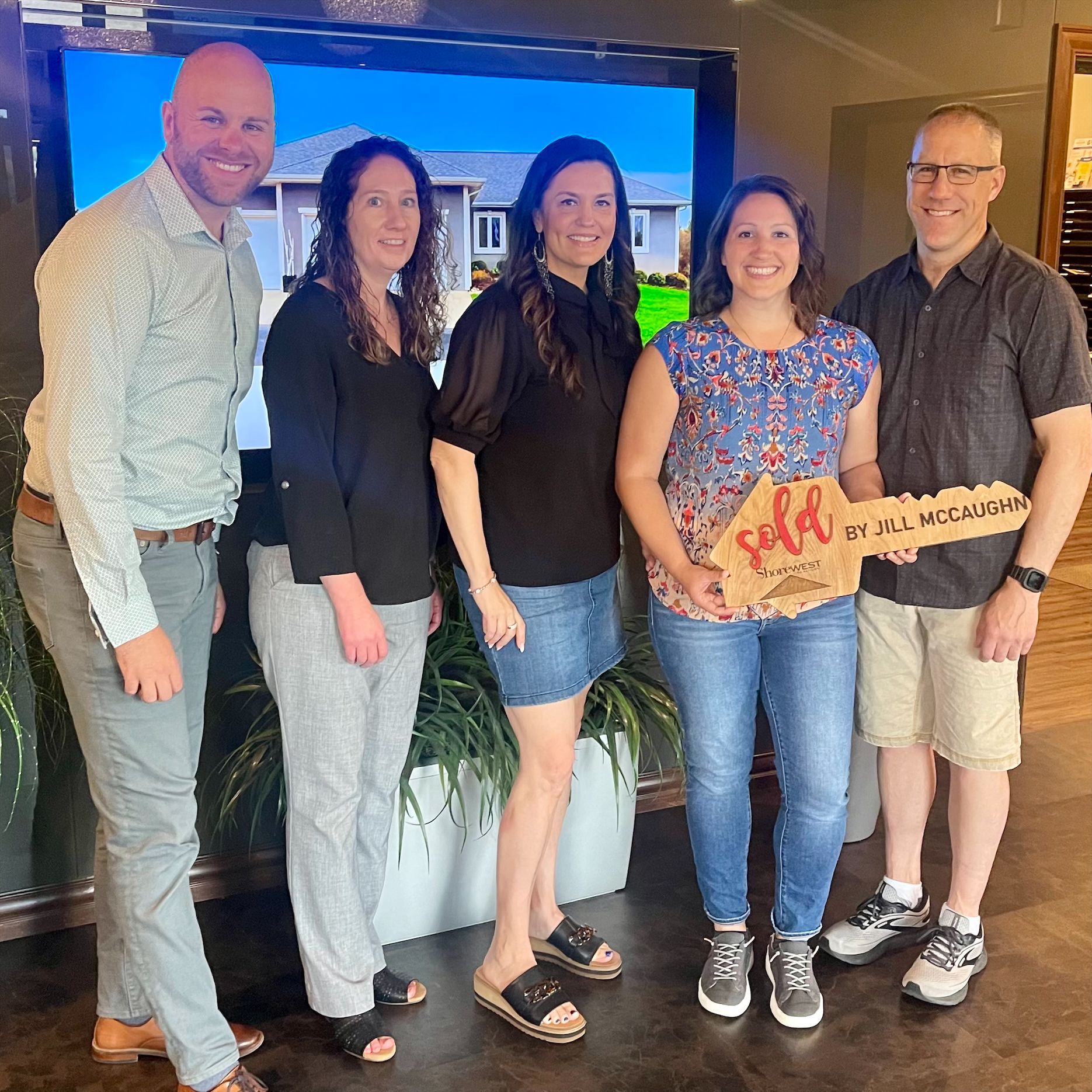 A group of people standing next to each other holding a house key.