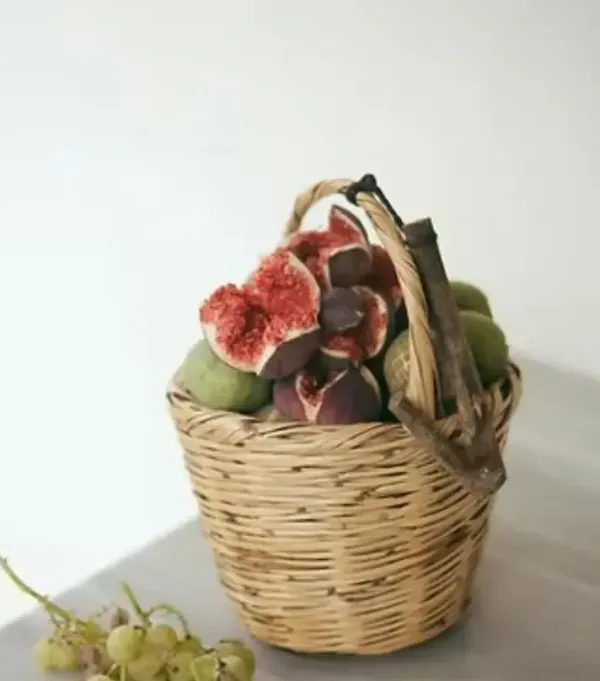 Basket of figs, some cut open to reveal red flesh, with grapes on the side.