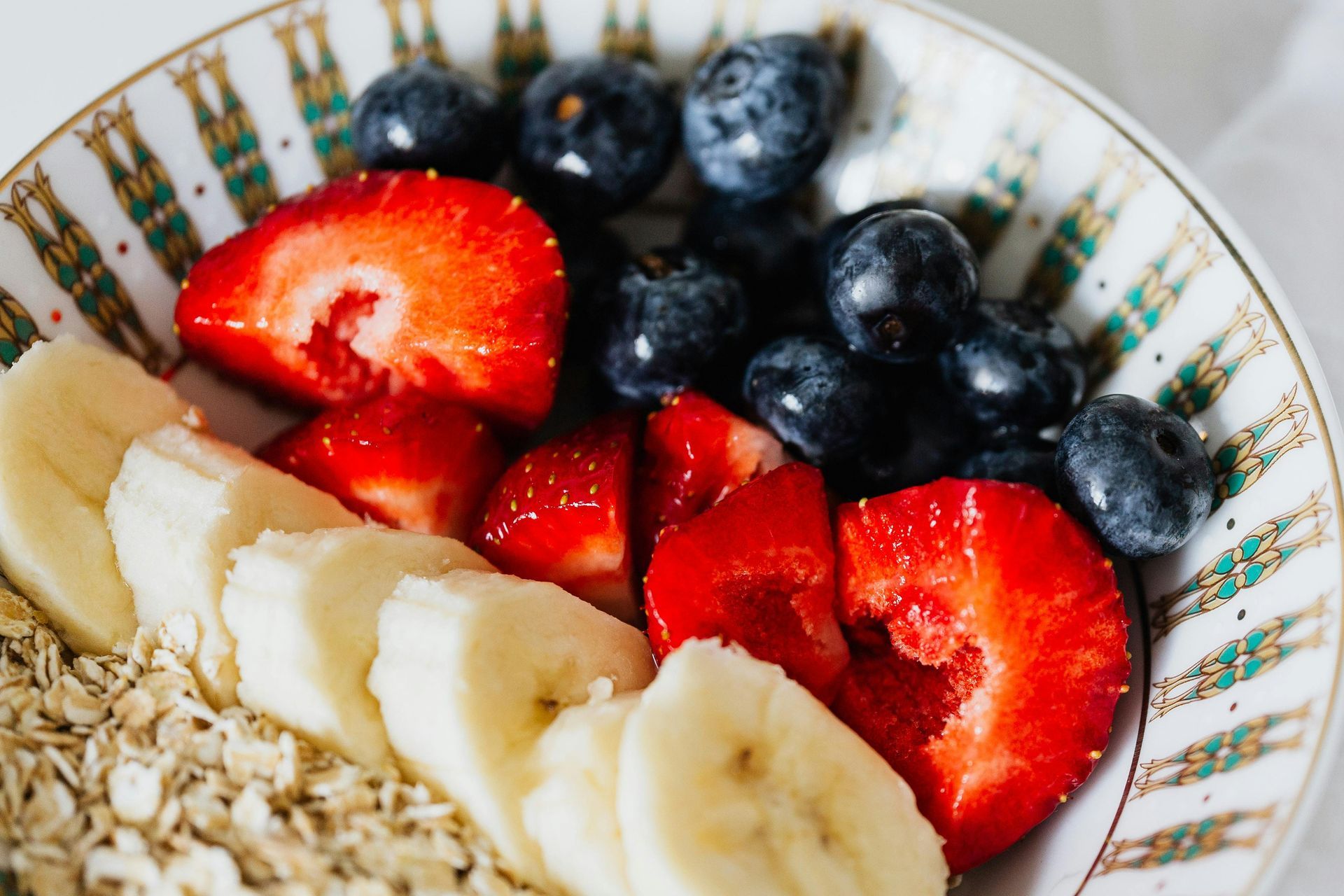 Bowl of oatmeal topped with sliced strawberries, blueberries, and banana.